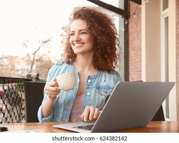 Schöne junge Frau mit Laptop im Café