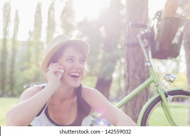 Beautiful young woman using mobile phone sitting next to her bike. - Powered by Shutterstock