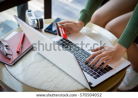 Beautiful young woman using portable laptop computer while sitting in the coffee shop. Young beautiful girl using a personal laptop computer to bill pay on the internet.
