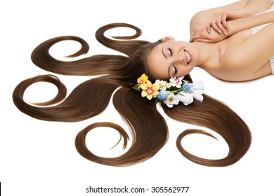 Beautiful young woman with very long natural hair and flowers on it lying on back. Isolated over white background.