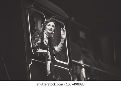 Beautiful Young Woman In A Vintage Antique Dress Gets Out Of The Train Driver’s Cab And Waves To Someone