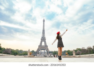 Beautiful young woman visiting paris and the eiffel tower. Parisian girl with red hat and fashionable clothes having fun in the city center and landmarks area