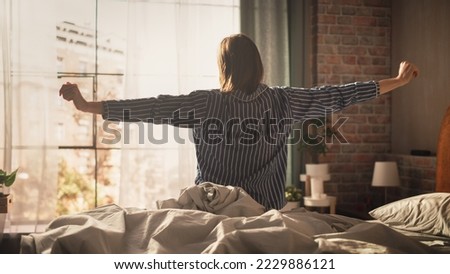 Beautiful Young Woman Waking up in the Morning, Stretches and Gets Out of Bed, Sun Shines From the Apartment Window into Bedroom, Ready for Business Opportunities, Achievements, Adventures