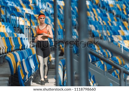 beautiful young woman walking by tribunes at sports stadium