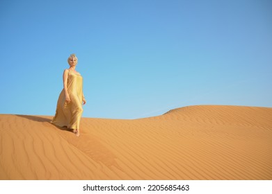 Beautiful Young Woman Walking On The Sand In The Desert.