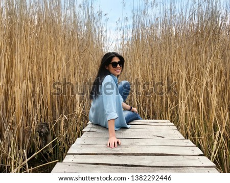 Beautiful Young Woman Walking on a Wooden Bridge in a Reed Marsh .People and Nature