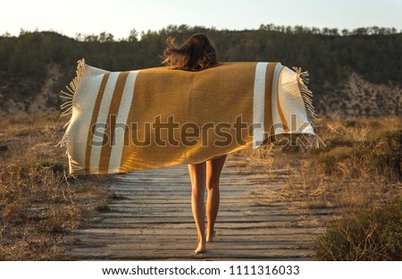 Beautiful young woman walking over a wood path wrapped with a wool towel
