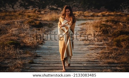 Beautiful young woman walking over a wood path wrapped with yellow a wool towel