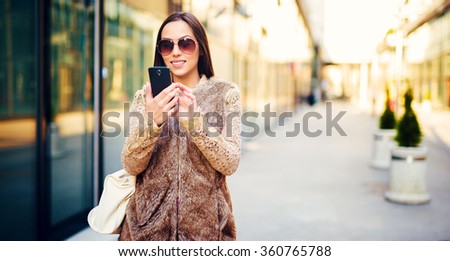 Beautiful young woman walking trough the city and typing on smart phone. 
