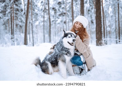 Beautiful young woman walks through the winter forest with her dog. A young woman with her pet on an adventure. Friendship concept, pets. Friendship between a woman and a dog.  - Powered by Shutterstock