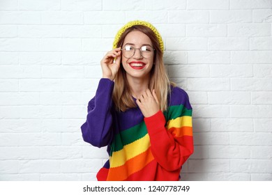 Beautiful young woman in warm sweater with hat near white brick wall - Shutterstock ID 1240778749