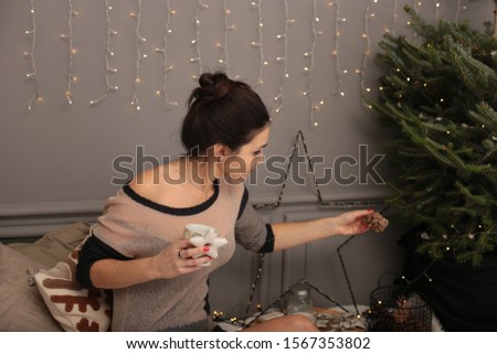 	
Beautiful young woman in a warm transparent sweater with gingerbread cookies and a cup of tea