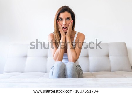 A beautiful young woman watching passionately TV in the living room.
