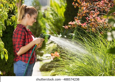 Beautiful Young Woman Watering Garden