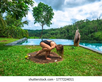 A Beautiful Young Woman Wearing A Black Sportive Swimsuit Is Practicing Yoga On The Rock Surrounded By Green Grass Next To The Swimming Pool In A Mountain Resort Near Galle City, Sri Lanka