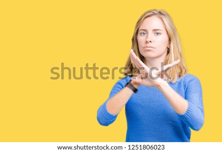 Beautiful young woman wearing blue sweater over isolated background Rejection expression crossing arms doing negative sign, angry face
