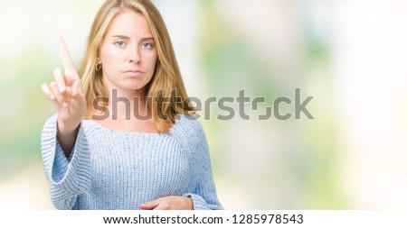 Beautiful young woman wearing blue sweater over isolated background Pointing with finger up and angry expression