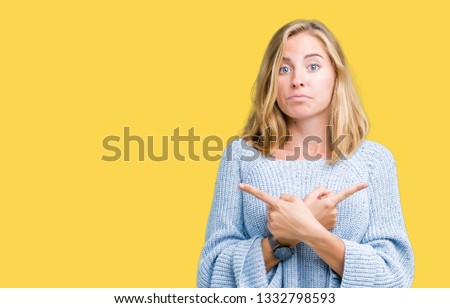 Beautiful young woman wearing blue sweater over isolated background Pointing to both sides with fingers, different direction disagree