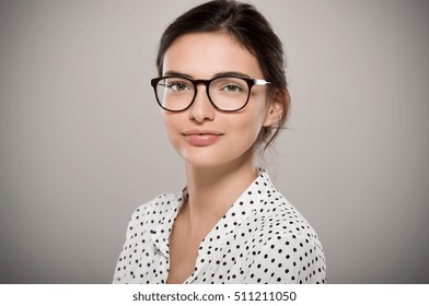 Beautiful young woman wearing eyeglasses isolated on grey background. Proud female student with nerd glasses looking at camera. Sophisticated glamour girl in shirt wearing big spectacles and smiling. 