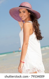 Beautiful Young Woman Wearing A Fancy Purple Hat And Enjoying The Pristine Crystal Clear Shoreline Of Miami's Beautiful South Beach.