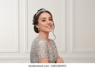 Beautiful young woman wearing luxurious tiara indoors