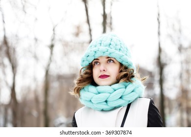 Beautiful young woman wearing merino wool pastel colors hat and scarf enjoying the fresh morning outdoors. Skin Care, Lip care, care of the eyelashes in the winter season.