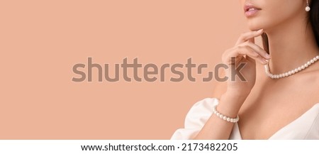 Beautiful young woman wearing stylish jewelry on beige background with space for text