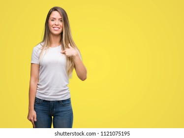 Beautiful young woman wearing t-shirt and jeans with surprise face pointing finger to himself