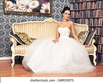 Beautiful Young Woman In Wedding Dress Sitting On Sofa