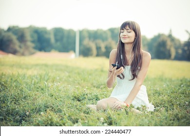 beautiful young woman with white dress listening music in the park - Powered by Shutterstock