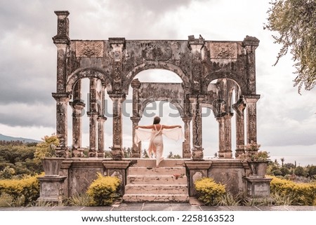 Beautiful young woman in a white dress in Water Palace Soekasada Taman Ujung Ruins on Bali Island in Indonesia.