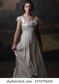 Beautiful young woman in a white long dress in the style of the 19th century. Portrait in the style of classical paintings