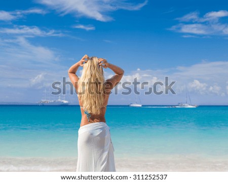  Beautiful young woman in white sarong on the beach.