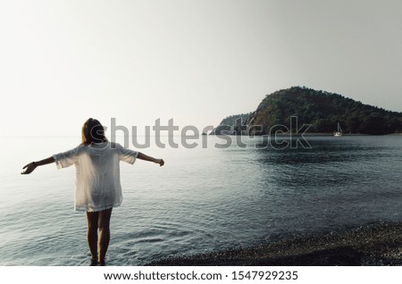Beautiful young woman in a white sundress walking along seashore