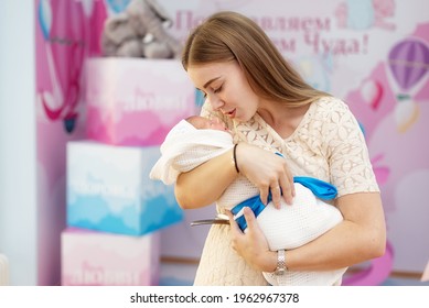 A beautiful young woman who recently gave birth to a baby is holding him in her arms, happy. Discharge from the maternity hospital