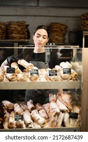 Beautiful Young Woman Working In A Bakery Shop, Bakery Owner At Work, Showcase With Pastry Assortment With Price Tags, Small Business Concept