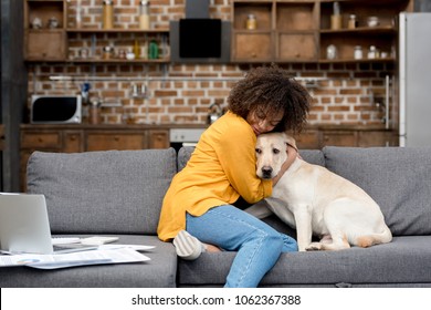 Beautiful Young Woman Working At Home And Cuddling With Her Dog