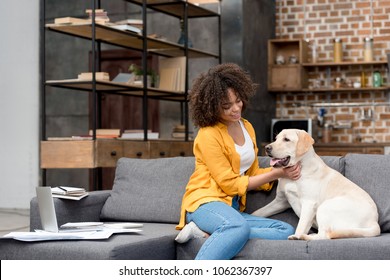 beautiful young woman working at home and petting her dog