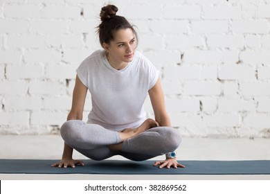 Beautiful young woman working out in loft interior, doing yoga exercise on blue mat, arm balance exercise with crossed legs, Scale Posture, Tolasana, Utpluthi Pose, full length - Powered by Shutterstock