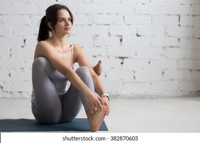 Beautiful Young Woman Working Out In Loft Interior, Doing Seated Hip Stretch, Hip Opener Eka Pada Agni Stambhasana, Warming Up On Blue Mat During Practice, Full Length, Copy Space