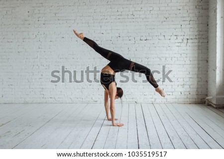 Beautiful young woman working out, yoga, Pilates, fitness training, doing a handstand