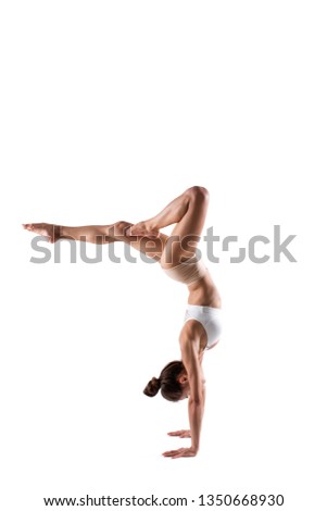 Beautiful young woman working out in studio. Handstand isolated, concept of healthy lifestyle, pilates, fitness and yoga.