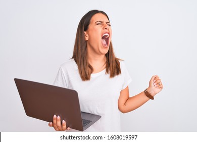 Beautiful Young Woman Working Using Computer Laptop Over White Background Angry And Mad Screaming Frustrated And Furious, Shouting With Anger. Rage And Aggressive Concept.