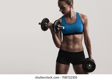 Beautiful Young Woman In A Workout Gear Lifting Dumbbells