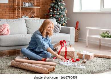 Beautiful Young Woman Wrapping Christmas Gifts At Home