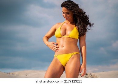 Beautiful young woman in yellow bikini applying sunscreen on her body