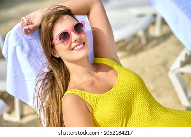 A Beautiful Young Woman In A Yellow Swimming Suit Sunbathing