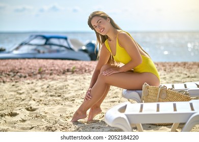 A Beautiful Young Woman In A Yellow Swimming Suit Sunbathing