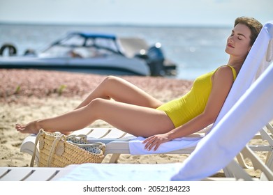 A Beautiful Young Woman In A Yellow Swimming Suit Sunbathing