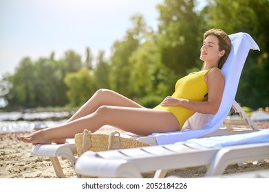 A Beautiful Young Woman In A Yellow Swimming Suit Sunbathing